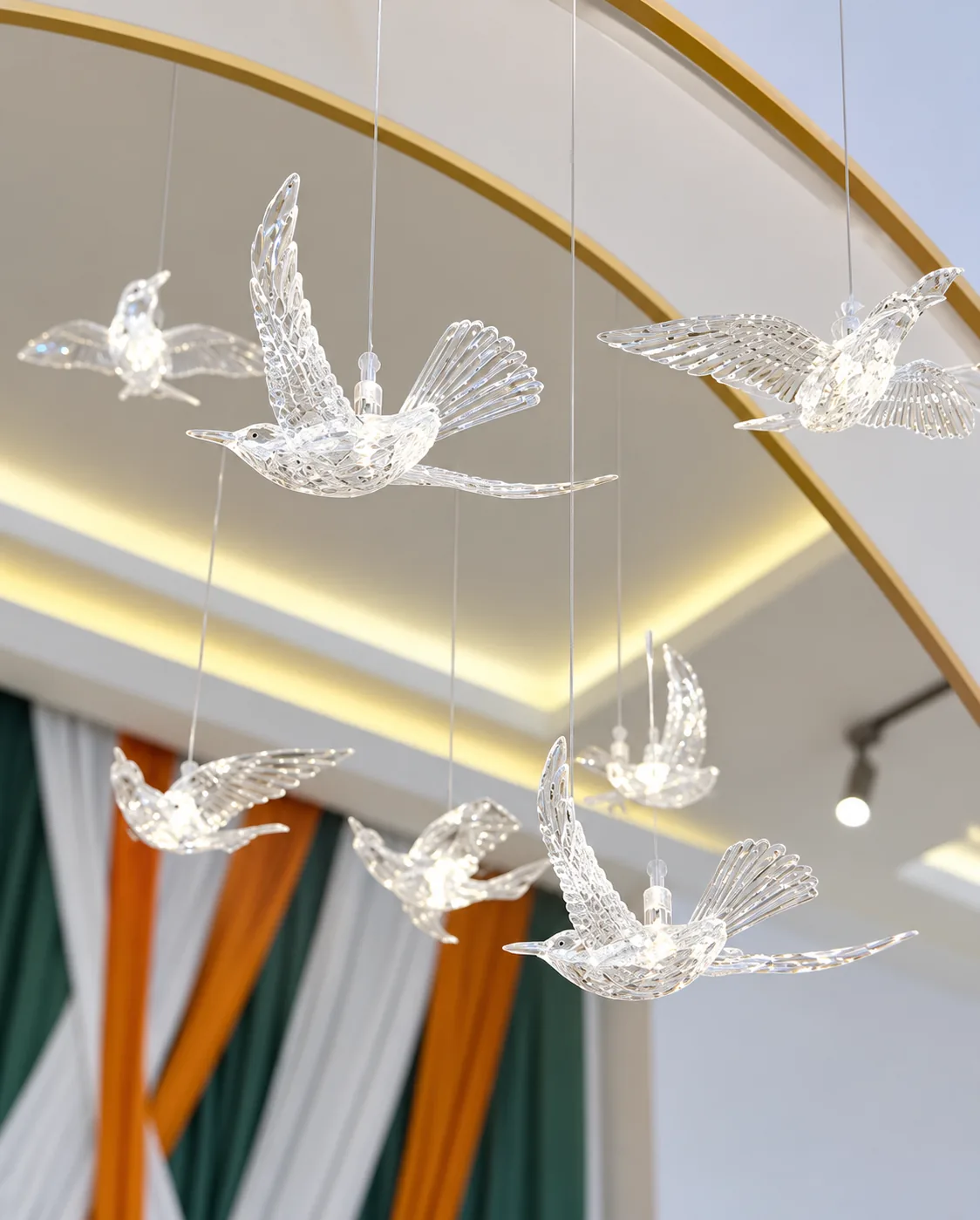 Oiseaux de cristal suspendus sous un plafond cerclé d’or